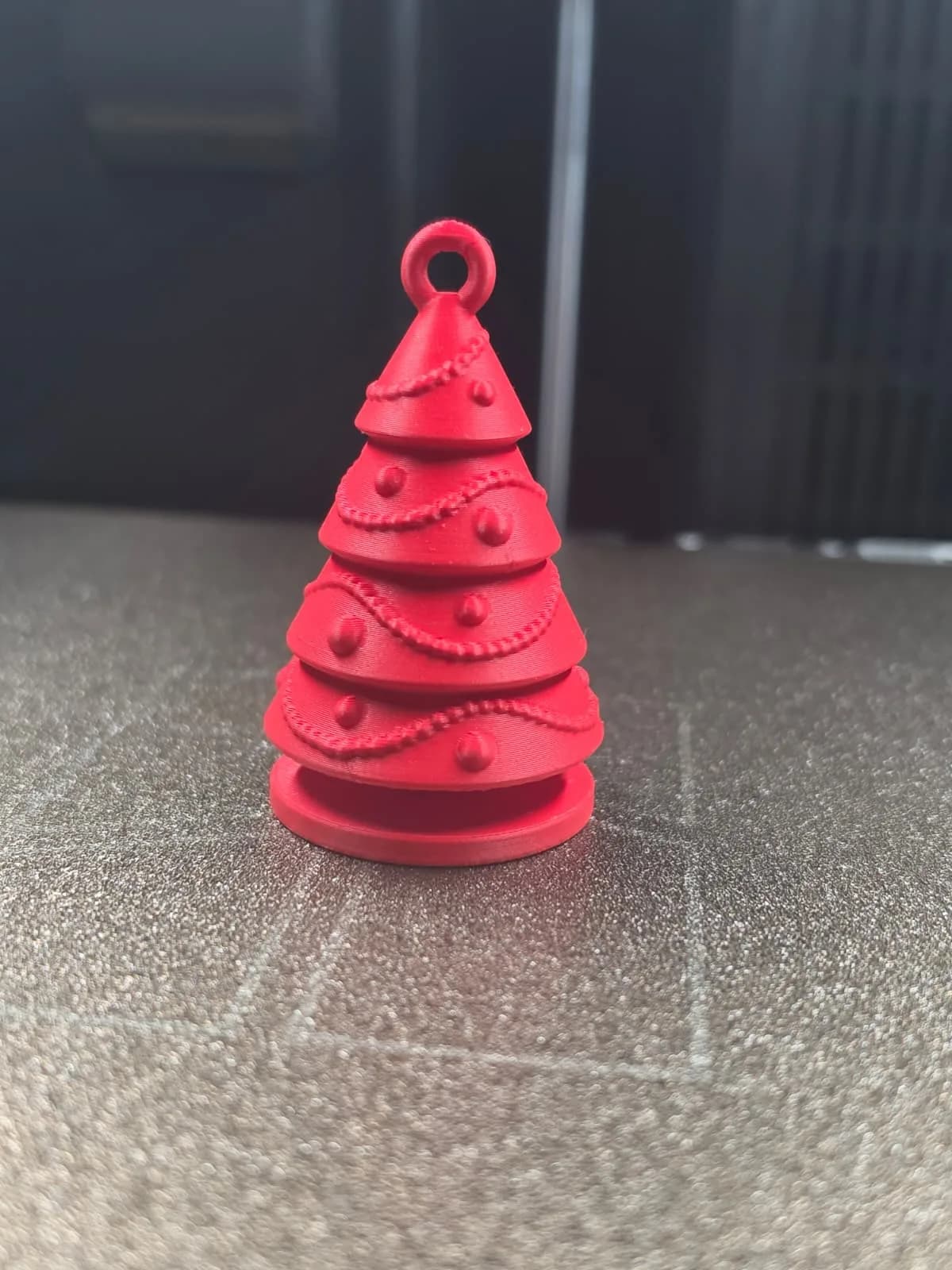 A red Christmas tree ornament with tiered branches, moulded garlands and round baubles, and a hanging loop at the top